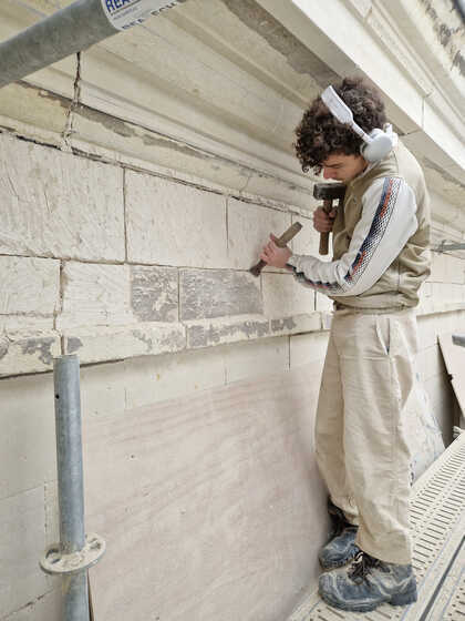 Tailleur de pierre œuvrant sur la façade du 2 place Sainte-Croix