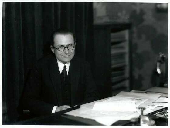 Portrait de Michel Roux-Spitz derrière son bureau en 1925