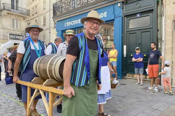 Bénévoles de l’association portant un tonneau de jus de raisin, en direction de l’hôtel de ville
